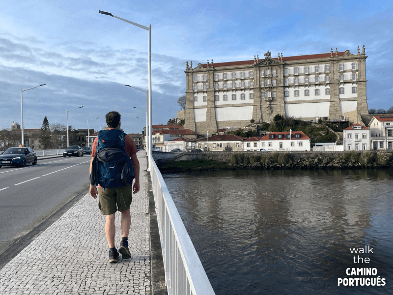 PIlgrim walking across the bridge into Vila do Conde with the Santa Clara monastery in the background